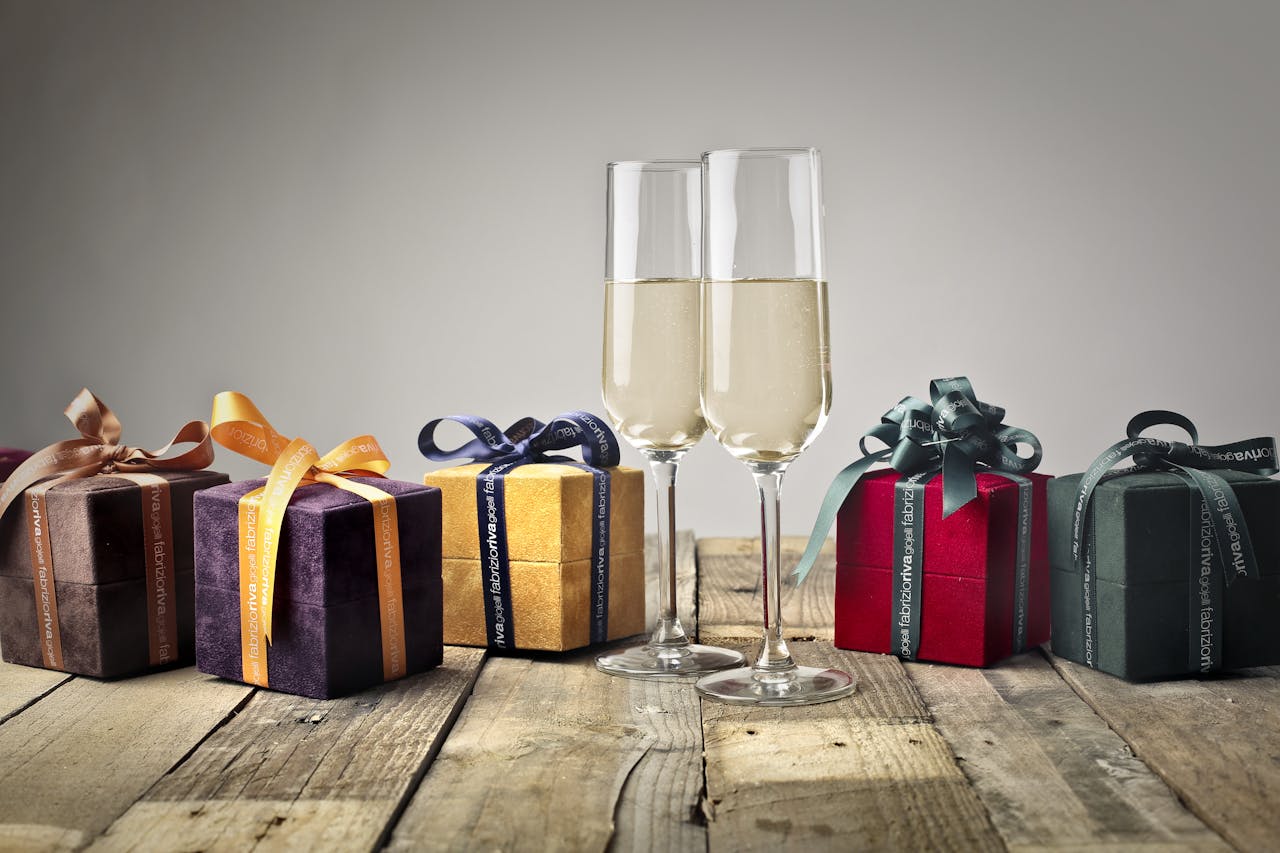 Luxurious gifts with ribbons and champagne flutes on a wooden table, perfect for celebrations.