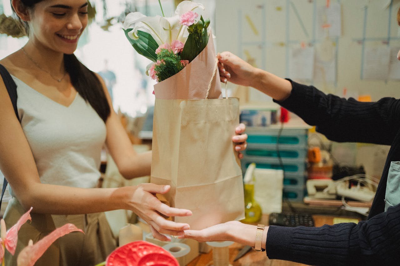 Smiling customer receiving a floral bouquet at a flower shop.